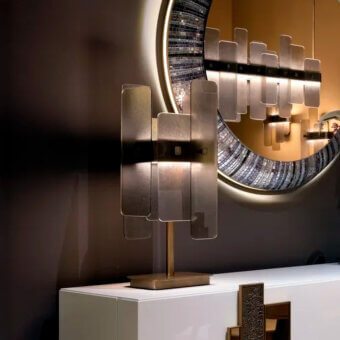 Sicis table lamp, brass and silver metal, layered rectangular plates, with mosaic mirror and dark brown wall backdrop.