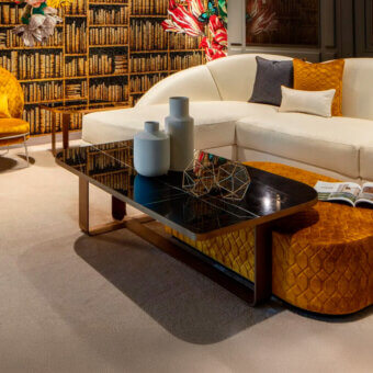 Sicis Visconti coffee table, black glass and gold metal, rectangular with curved legs, styled with vases and ottoman in a luxury interior.