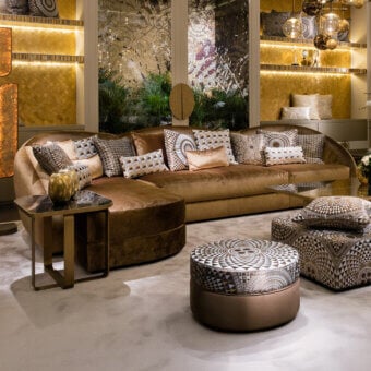 Sicis Visconti sectional sofa, brown textured fabric, asymmetrical rounded shape with patterned pillows and marble side table.