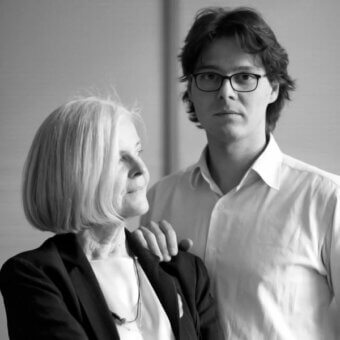 Black and white portrait of Antonia Astori and Nicola de Ponti, featuring a woman in a blazer and a man in a white shirt against a gray wall.