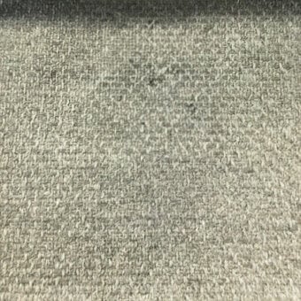 Gray woven fabric texture displaying a heathered, mottled pattern with a slightly rough surface and consistent, intricate weave details.