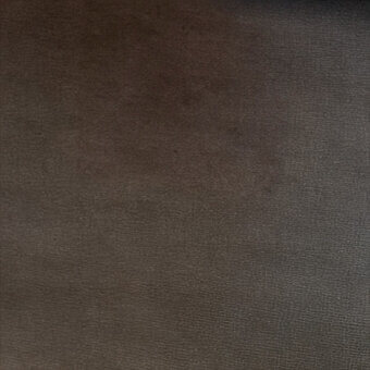 Brown textured upholstery material with a granular woven finish and diffused lighting, displaying subtle tonal variations throughout the surface.