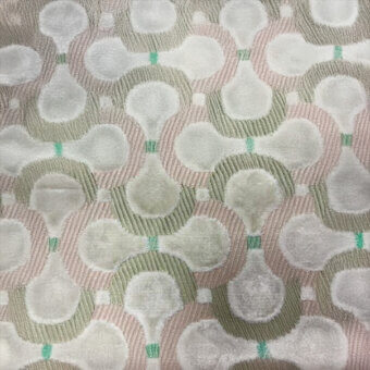 Pale pink textile with repeating off-white teardrop shapes and muted green lines in a grid pattern, featuring a textured woven surface.