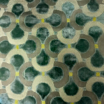 Geometric textile sample, dark teal and beige, features circular patterns with yellow accents, woven with a plush velvety texture.