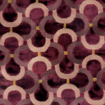 Burgundy velvet textile with repeating circular pattern, connected by woven beige and gold bands, featuring overlapping shapes and gold dots.