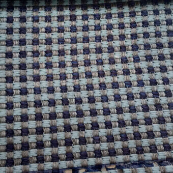 Textile sample with checkerboard pattern in sage green, indigo, and beige; simple over-under weave creates a matte, textured surface.