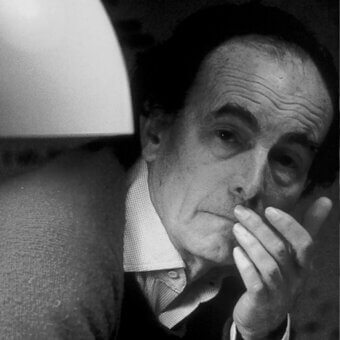 Black and white portrait of Giuseppe Ostuni in a suit, hand to mouth, with diffused light from a rounded lampshade and textured wall backdrop.