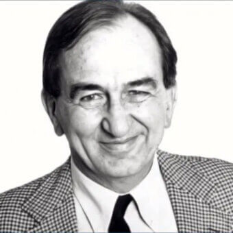 Marco Zanuso portrait, black and white photograph, man in checkered blazer, light shirt, navy tie, formal studio lighting, neutral expression.