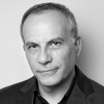 Black and white portrait of Stefano Casciani, a man with graying hair wearing a brown blazer and dark collared shirt, facing forward.