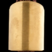 Brushed brass cylinder with vertical band, rounded top, and tapered base, held in a hand against a dark backdrop.