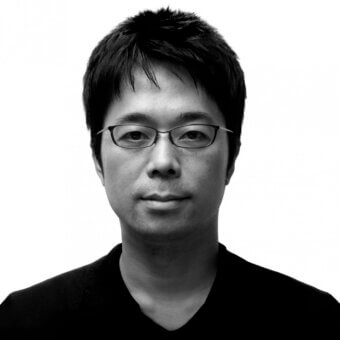 Black and white portrait of Tokujin Yoshioka, a man with short dark hair, wearing rectangular glasses and a v-neck shirt.