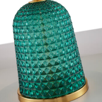 Cloche table lamp, teal glass with diamond facets, brushed brass base, cylindrical shade, flared form, studio lighting, gray surface.
