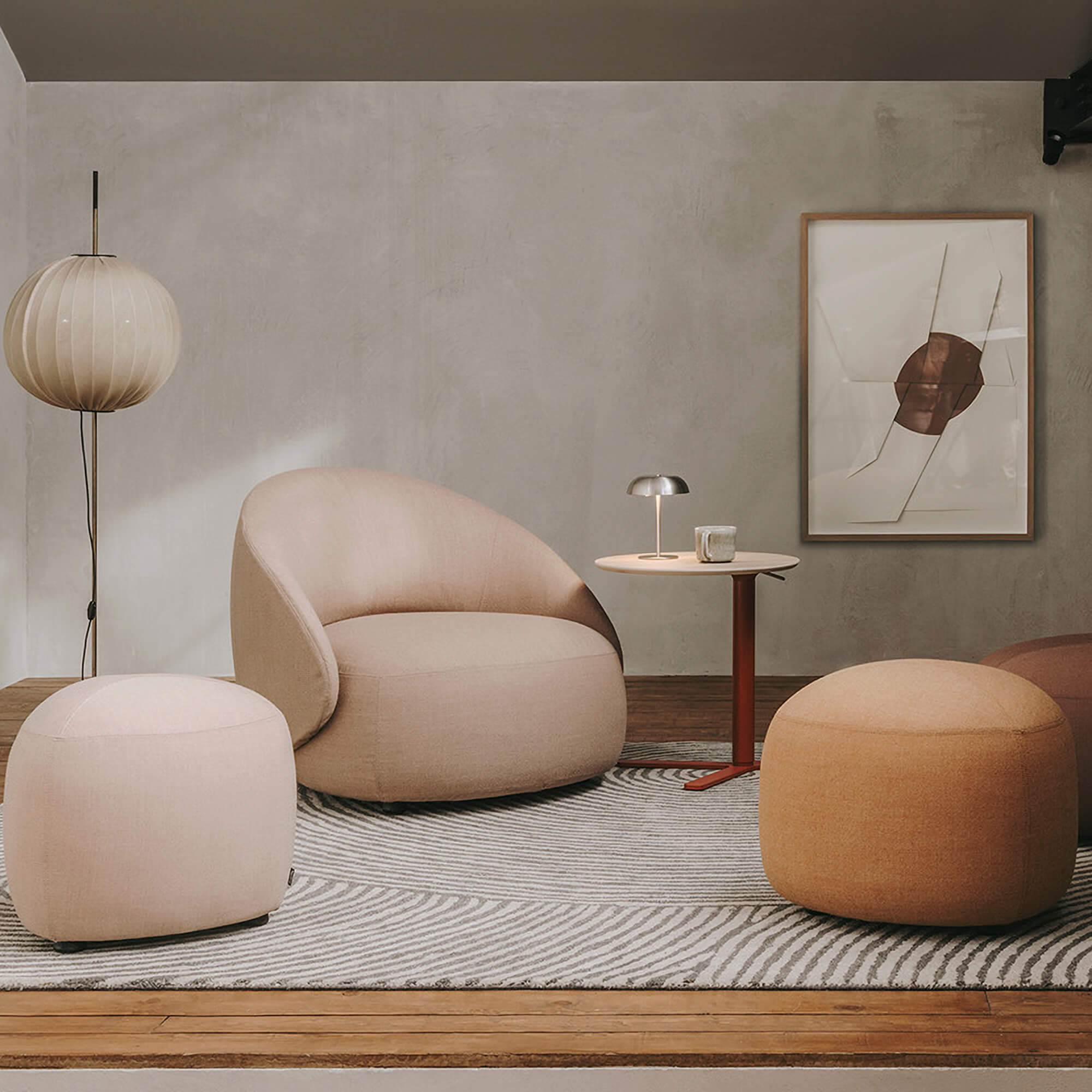 Lapalma Kipu club chair, beige fabric, rounded form, with terracotta ottoman and dark wood side table in a minimalist interior.