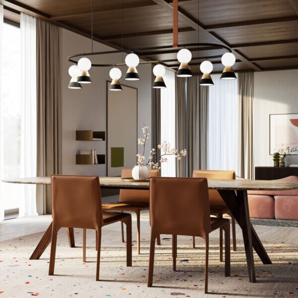 Dining room with wood table, eight leather chairs, linear chandelier, beige curtains, mirror, and patterned rug; Cassoni 2025 collection.