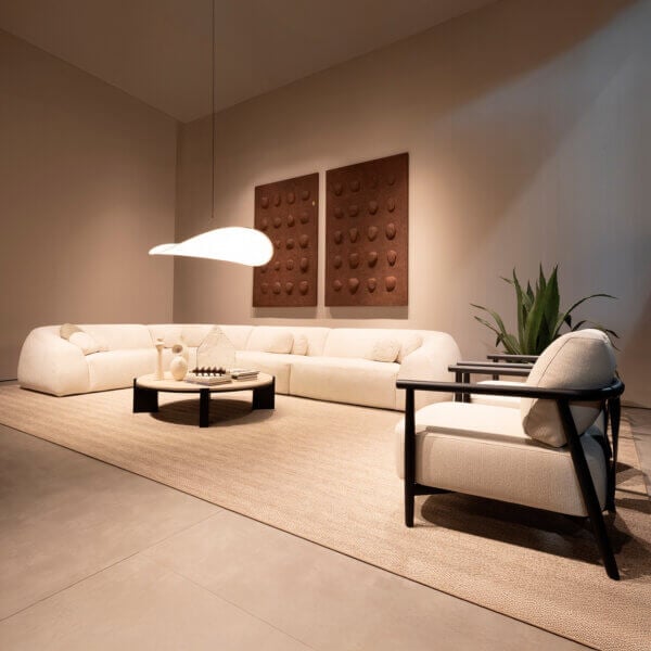 Cream modular sofa with chaise, jute rug, dark gray stone coffee table, and cream armchair in a beige living room.