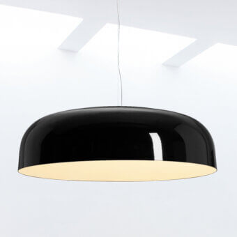 Cassoni Oluce suspension lamp, black metal, shallow dome shade reflects light against a white ceiling with recessed fixtures.