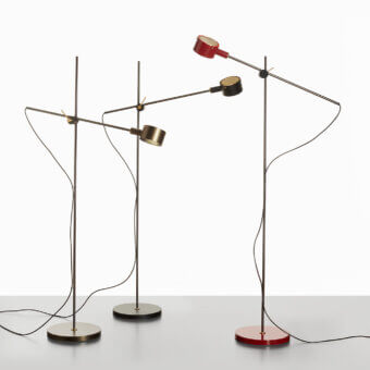 Distinguished Oluce G.O. floor lamp with a polished brass-toned base and dark gray lampshade exhibiting a subtly brushed metallic finish