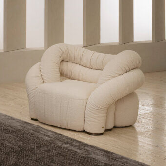 Lavish Rugiano Abbraccio lounge chair upholstered in creamy off-white fabric with elegant bronzed brass details