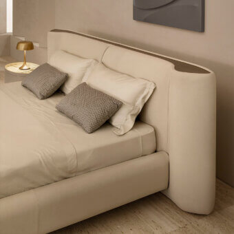 Exclusive Rugiano Anais bed with a rounded headboard and plush frame upholstered in neutral beige fabric with bronzed brass details