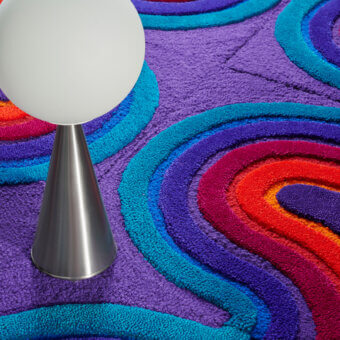 Distinguished Amini Domino rug crafted from New Zealand wool with vibrant purple, blue, orange, and red hues and a hand-washed carved texture