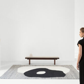 Lavish Amini Jean rug displaying a hand-clipped asymmetrical design woven with 100% wool in shades of ivory, dark grey, and brown