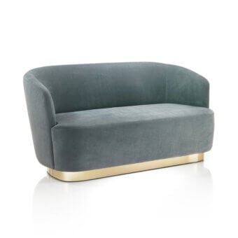 Coco sofa, dusty teal velvet, rounded cocoon shape with brass base and curved armrests, studio product shot.