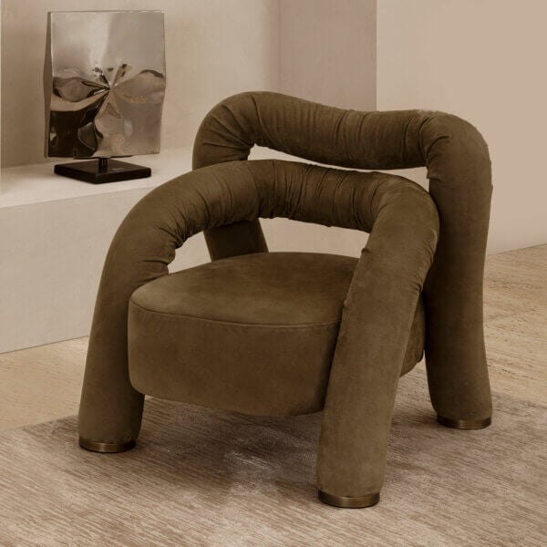 Olive-green armchair with rounded, continuous form and velvety upholstery, positioned before a metallic swirling sculpture on a black base.