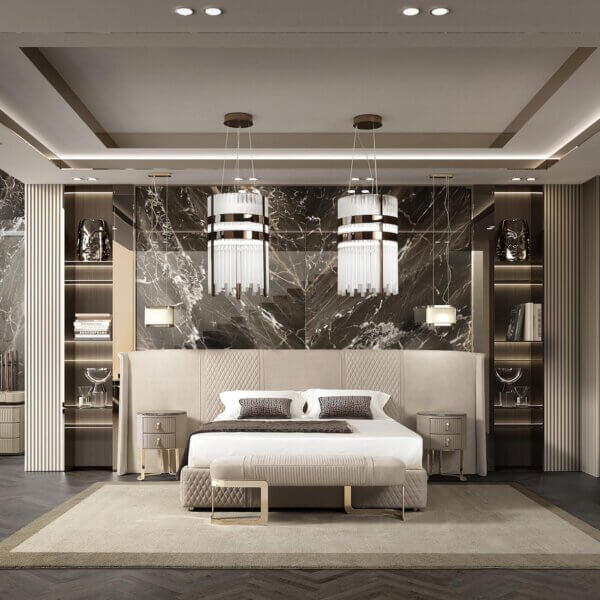 Platform bed, beige upholstery, quilted headboard with gold nightstands, dark marble wall, pendant lights, and stacked books.