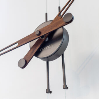 Distinguished Nomon Péndulo Pendulum Clock timepiece with a steel cable, dark metal cylinder and satin-finish wooden arms