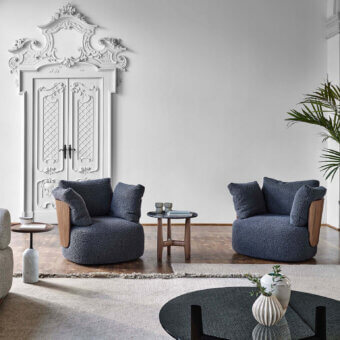 Elegant Porada Calin armchair built with curved Canaletto walnut and fully upholstered dark blue-grey bouclé textile with a sleek swivel metal base