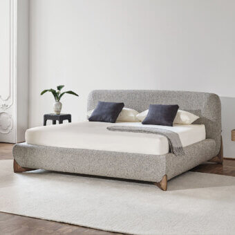 Lavish Softbay Bed Max bed upholstered in light gray textured textile with a gracefully wrapping canaletto walnut frame