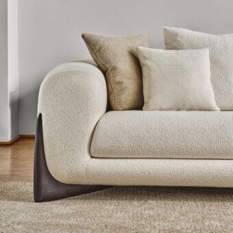 Sumptuous Porada Softbay sofa with curved silhouette and inviting upholstery in cotton, linen, and wool bouclé with a satin Canaletta walnut base