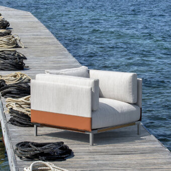 Exceptional Ethimo Baia lounge chair upholstered in textured light neutral fabric with reddish-brown fabric panel detail for indoor-outdoor use