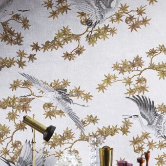 Exclusive LondonArt Sya wallpaper presents stylized cranes and foliage in grey and metallic gold with a matte non-woven finish