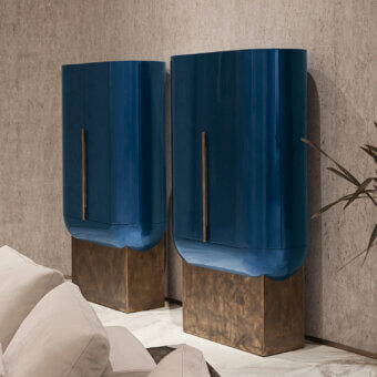 Distinguished Visionnaire Siona bar cabinet with rounded form and deep teal blue glossy synthetic material built on a golden textured base