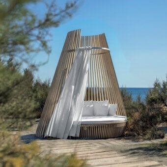 Distinctive Ethimo Hut daybed crafted in light to medium-toned wood with flowing white textiles and a satin finish