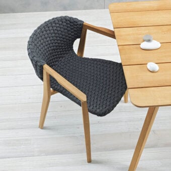 Captivating Ethimo Knit armchair with dark charcoal gray woven texture and sinuous hand-finished FSC-certified teak frame