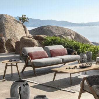 Sophisticated Ethimo Knit sofa with a sinuous teak frame and lavish reddish-brown cushions in a medium gray textile weave