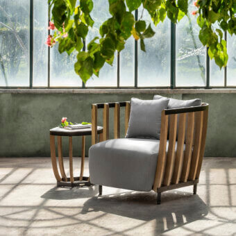 Elegant Ethimo Swing lounge chair crafted with a metal frame, warm teak slats and gray textile cushion with a satin finish