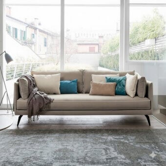 Superior Dallagnese Milton sofa upholstered in smooth matte beige textile with teal cushions and sleek angled legs