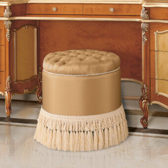 Sumptuous Modenese Royal Blend round ottoman crafted with golden-beige upholstery and delicate fringe detailing