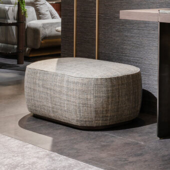 Superior Zanaboni Alma ottoman with gray textile upholstery and gray-stained ash base offers a rounded asymmetrical form