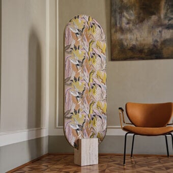 Exclusive Black Tie Tìam mirror with curved glass displaying ochre, pale pink, grey, and white botanical patterns in travertine