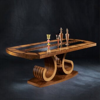 Distinguished Carpanelli Arts extendable table crafted in walnut and birdseye maple with a glossy finish and intertwined volute base