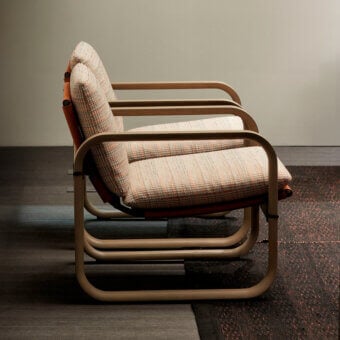 Elegant Giorgetti Loop lounge chair with water-polished grey ash wood and carob aluminum, crafted with textured peach textile upholstery and leather straps