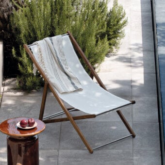 Distinguished Atmosphera Nirvana deck chair with Asian teak frame, brushed steel accents, and breathable off-white textilene seat, oil finish
