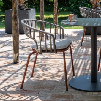 Distinguished Atmosphera Onda armchair with gracefully curved silhouette and braided light gray textile with reddish-brown coated metal frame