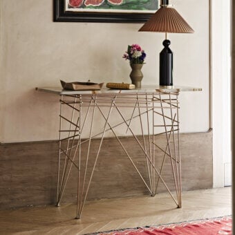 Elegant Black Tie Lin console with clear glass top and coppery-gold toned steel base exhibiting a satin finish
