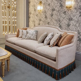 Elegant sofa woven fabric/linen blend matte finish curved camel‑back rail integrated arms dark teal tassels brown beads