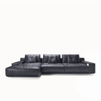 Elegant sectional with dark charcoal gray leather, slightly glossy, L‑shaped silhouette, metal armrests, brutalist‑inspired block and void arrangement